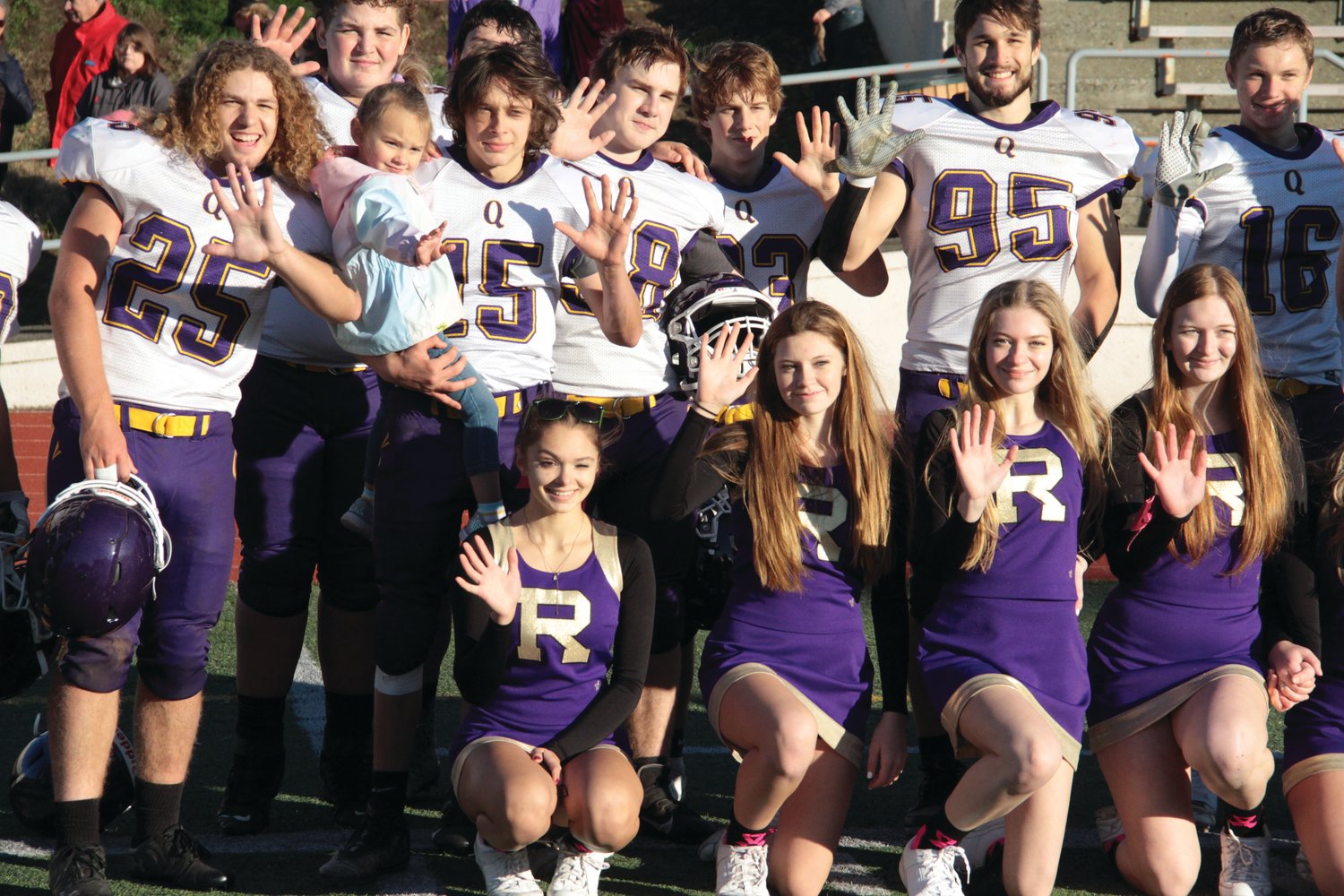 Members of the Quilcene Rangers football team and cheer squad flash fives during an after-game photo on the field following the win against Evergreen Lutheran.